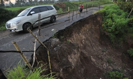 Kendaraan melintasi sebagian badan jalan yang longsor  (ilustrasi)