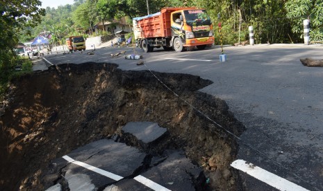 Kendaraan menghindari jalan yang ambles dan longsor di Sawoo, Ponorogo, Jawa Timur, Selasa (25/4). 