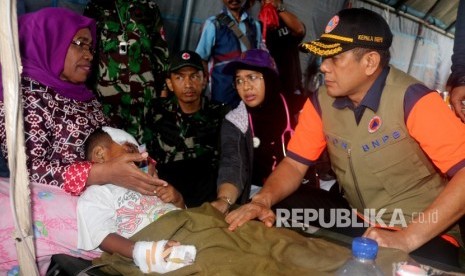 Kepala Badan Nasional Penanggulangan Bencana (BNPB) Doni Monardo (kanan) mengunjungi pasien korban gempa yang dirawat di rumah sakit lapangan yang dibangun TNI di kompleks Kampus Universitas Darussalam, Desa Tulehu, Pulau Ambon, Kabupaten Maluku Tengah, Maluku, Jumat (27/9/2019). 