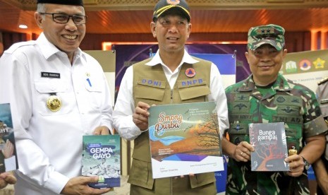 Kepala Badan Nasional Penanggulangan Bencana (BNPB) Letjen (TNI) Doni Monardo (tengah) bersama Pj. Gubernur Aceh Nova Iriansyah (kiri) dan Panglima Kodam Iskandar Muda Mayjen TNI Teguh Arief Indratmoko, memperlihatkan buku tentang kebencanaan Aceh, di Banda Aceh, Aceh, Rabu (7/8/2019).