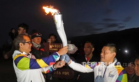 Kepala Balai Besar KSDA Jawa Timur Nandang Prihadi (kiri), menerima obor Asian Games 2018 dari mantan petinju Pino Bahari di puncak Gunung Ijen, Banyuwangi, Jawa Timur, Ahad (22/7). 