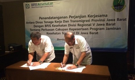 Kepala BPJS Kesehatan Divisi Regional V Jawa Barat Mohammad Edison (kiri) menandatangani kesepakatan kerja dengan Kepala Dinas Tenaga Kerja dan Transmigrasi Provinsi Jawa Barat Ferry Sofwan Arif di Kota Bandung, Rabu (19/4).