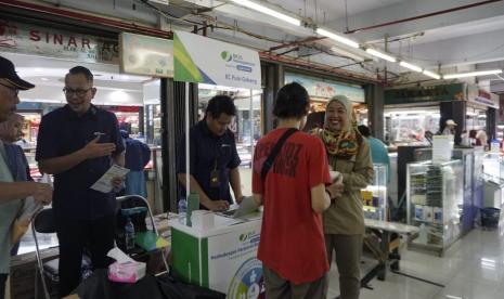 Kepala BPJS Ketenagakerjaan Cabang Jakarta Pulo Gebang Dewi Mulya Sari memberikan edukasi soal program jaminan perlindungan ke pekerja informal di Pasar Klender, Jakarta Timur, Senin (11/12/2023).