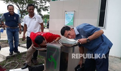 Kepala Dinas Pekerjaan Umum Cipta Karya Sumatera Selatan (Sumsel) Basyarudin (kanan) dan Asisten Pemerintah Provinsi Sumsel bidang Pemerintahan dan Kesejahteraan Rakyat Achmad Najib (kiri) mencoba minum air dari kran air siap minum (KASM) yang ada di Kompleks Jakabaring Sport City (JSC) yang dipersiapkan untuk menghadapi Asian Games 2018. 