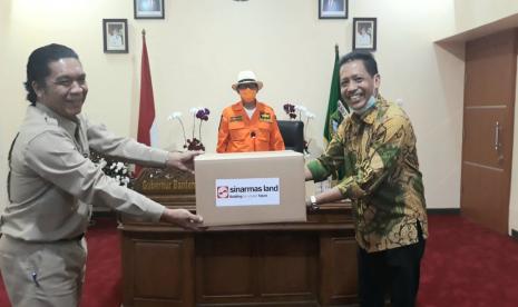 Kepala Divisi Corporate Affairs Sinar Mas Land, Dony Martadisata (kanan) menyerahkan bantuan Alat Pelindung Diri (APD) secara simbolis kepada Sekretaris Daerah Propinsi Banten Dr. Al Muktabar MSc (kiri) disaksikan oleh Gubernur Provinsi Banten, Dr. Wahidin Halim (tengah). Penyerahan 750 set APD ini berlangsung di  kediaman Gubernur Banten (31/3).   