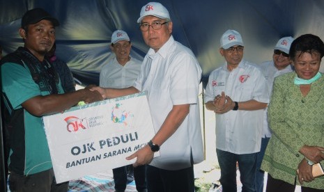 Kepala Eksekutif Pengawas IKNB Otoritas Jasa Keuangan (OJK) Riswinandi (tengah) bersama Ketua Dewan Komisioner Wimboh Santoso (ketiga dari kanan), Kepala Eksekutif Pengawas Perbankan Heru Kristiyana (kedua kiri) dan Kepala Eksekutif Pengawas Pasar Modal Hoesen (kedua kanan) menyerahkan bantuan sarana MCK kepada korban gempa di Desa Lolu, Sigi, Sulawesi Tengah, Kamis (18/10/2018).