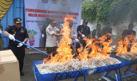 Kepala Kantor Pengawasan dan Pelayanan Bea dan Cukai (KPPBC) Tipe Madya Pabean C Jember Asep Munandar (kiri), didamping Kepala Satuan polisi Pamong Praja Situbondo Buchari (kedua kiri), memusnahkan barang bukti rokok ilegal di Kantor Bantu Panarukan, Situbondo, Jawa Timur, Jumat (26/8/2022). Kantor Bea Cukai setempat memusnahkan sebanyak 909.392 batang rokok ilegal hasil penindakan tahun 2020-2021 dengan potensi kerugian negara sebesar Rp1,2 miliar. 