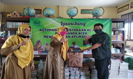 Kepala MIN 11 Banda Aceh Dahrina menyerahkan cinderamata kepada koordinator pengembangan perpustakaan Nazaruddin.