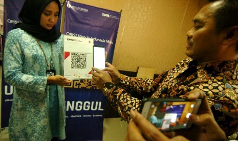 Kepala Perwakilan Bank Indonesia (BI) Tegal, M.Taufik Amrozy (kanan) mempraktekkan pembayaran melalui aplikasi uang elektronik 'server based', dompet elektronik dan mobile banking saat peluncuran QR Code Indonesian Standard (QRIS) di Tegal, Jawa Tengah, Selasa (20/8/2019). 