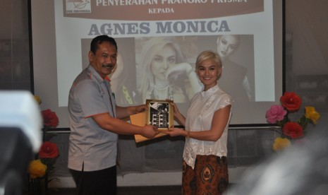 Kepala Regional 4 Jakarta Pos Indonesia Pupung Purnama (kiri) menyerahkan prangko prisma kepada penyanyi Agnez Mo (kanan) sebagai brand ambassador Pos Indonesia di Kantor Pos Fatahilah Kota Tua Jakarta Barat, Senin (25/9).