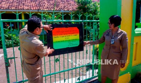 Kepala Sekolah dan guru memasang papan informasi sekolah diliburkan di SD Negeri Denasri Wetan 02, Kabupaten Batang, Jawa Tengah, Senin (16/3/2020).(Antara/Harviyan Perdana Putra )