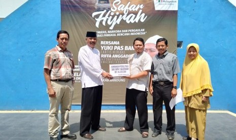 Kepala  SMPN 1 Baleendah, Kabupaten Bandung Asep Juhro (kedua dari kiri) menyerahkan secara simbolik bantuan uang untuk palu dari siswa dan guru kepada relawan  Yayasan Harapan Amal Mulia, Riffa Anggadhitya di Kampus SMPN 1 Baleendah, Kabupaten Bandung, Selasa (16/10).