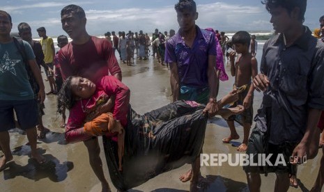 Kerabat membawa seorang wanita Muslim Rohingya, yang jatuh pingsan saat kapal yang dia tumpangi berbaris beberapa menit sebelum mencapai pantai, menuju pusat perawatan medis di Shah Porir Dwip, Bangladesh, Kamis, (14/9).