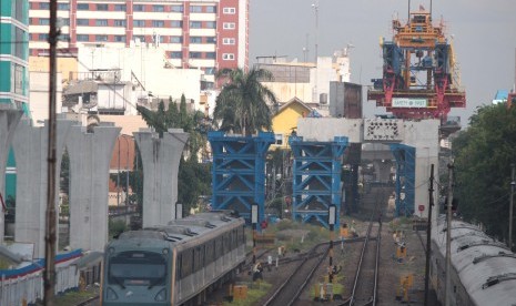 Kereta api bandara melintas di samping proyek pembangunan rel layang di Stasiun Besar Medan, Sumatra Utara. 