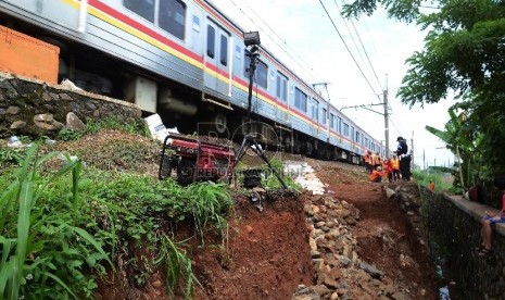 Kereta Commuter Line (KRL) dari Bogor menuju Jakarta berjalan perlahan saat melintasi longsoran pinggir rel di dekat Stasiun Citayam, Depok, Rabu (25/11).