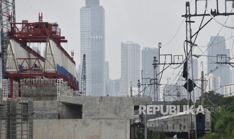 Kereta jarak jauh melintas di samping proyek pembangunan konstruksi jalur rel dwi ganda double-double track di Jakarta Timur, Jumat (2/2). 