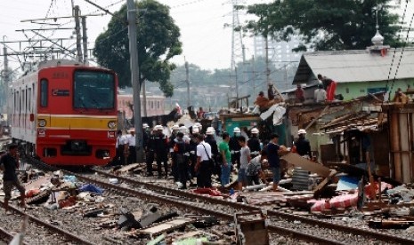 Kereta melintas di sela pembongkaran bangunan liar di skeitar stasiun. 