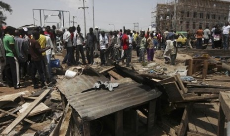 Kerumunan orang yang menyaksikan kerusakan akibat ledakan bom di Kaduna, Nigeria, Senin (9/4).