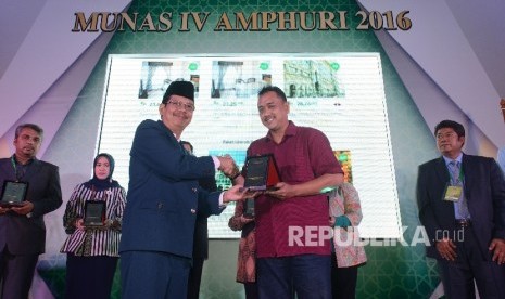 Ketua Asosiasi Muslim Penyelenggara Haji dan Umrah Republik Indonesia (Amphuri) Joko Asmoro (kiri) memberikan piagam penghargaan kepada Manajer Iklan Harian REPUBLIKA Indra Wisnu Wardhana (kanan) saat musyawarah nasional ke-IV yang diadakan di Bogor, Jawa 