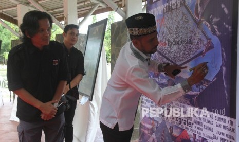 Ketua Dewan Perwakilan Rakyat Aceh (DPRA) Muharuddin (kanan) didampingi Ketua Pewarta Foto Indonesia (PFI) Aceh Fendra Trysani (kiri) menandatangi banner pemeran foto peringati tsunami sebagai pertanda pembukaan pameran di Taman Putroe Phang, Banda Aceh, Aceh, Senin (25/12).