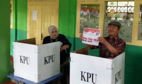 Ketua DKPP, Jimly Asshiddiqie (kanan) dan sang istri (kiri) sedang berada dibalik suara di TPS 021 Pondok Labu, Jakarta Selatan, Rabu (15/2). 