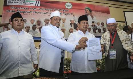 Ketua Gerakan Nasional Pengawal Fatwa Ulama (GNPF-U) Yusuf Muhammad Martak (tengah) bersama bakal calon presiden Prabowo Subianto (kanan) didampingi Wakil Ketua Umum Partai Gerindra Fadli Zon (kiri) menunjukkan naskah pakta intregitas yang telah ditandatangani dalam acara Ijtima Ulama II dan Tokoh Nasional di Jakarta, Minggu (16/9). 