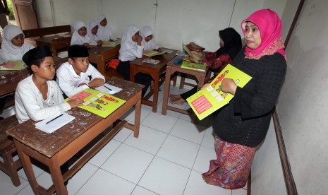 Ketua Himpunan Wanita SKK Migas (HWS) Luthfia Amien Sunaryadi (kanan) memberikan penjelasan tentang buku migas kepada siswa-siswi Madrasah Diniyah Awaliyah di Kampung Sukadiri, Kota Serang, Banten, Rabu (16/3).