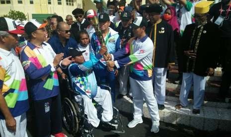 Ketua Inapgoc Raja Sapta Oktohari menyerahkan obor Asian Para Games 2018 kepada atlet difabel Ternate Risal Assor di halaman Kedaton Sultan Ternate, Ahad (9/9).