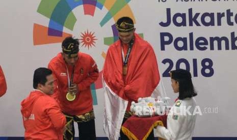 Ketua Inasgoc Erick Thohir mengalungkan medali kepada Pesilat Indoensia Yola Primadona Jampil dan Hendy pada final cabang pencak silat kelas artistik ganda putra Asian Games 2018 di Padepokan Pencak Silat TMII, Jakarta, Senin (27/8). 