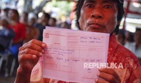 Ketua Kelompok Pokmas Tibu Harapan Desa Dara Kunci Purna (40) menunjukkan kwitansi untuk pemindahbukuan rekening ke rekening aplikator dana bantuan gempa untuk tahap pertama bagi tiga belas kepala keluarga anggotanya di Dusun Pedamekan, Desa Sambelia, Lombok Timur, NTB, Kamis (18/10/2018).