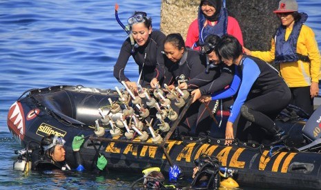 Ketua Kongres Wanita Indonesia (Kowani) (kiri) Giwo Rubianto Wiyogo bersama sejumlah perempuan mengangkat terumbu karang yang akan dilepaskan ke dalam laut di Kupang, NTT Jumat (11/12).