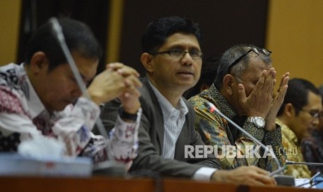 Ketua KPK Agus Raharjo (kanan) memengusap wajahnya bersama dengan Wakil Ketua KPK Laode M. Syarif (tengah) yang tengah memberikan pemaparan saat Rapat Dengar Pendapat (RDP) bersama Komisi II di Kompleks Parlemen, Jakarta, Rabu (15/6).  