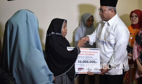 Ketua KPU Arief Budiman (kedua kanan) menyerahkan santunan uang kepada keluarga almarhum Umar Madi, petugas KPPS yang wafat, di kelurahan Sukabumi Selatan, Kebon Jeruk, Jakarta Barat, Jumat (3/5/2019). 