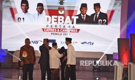 Ketua KPU Arief Budiman (kiri) bersama pasangan capres-cawapres nomor urut 01 Joko Widodo (kanan) dan Ma'ruf Amin (ketiga kanan) serta pasangan nomor urut 02 Prabowo Subianto (kedua kiri) dan Sandiaga Uno (kedua kanan) bersiap mengikuti debat pertama Pilpres 2019, di Hotel Bidakara, Jakarta, Kamis (17/1/2019). 