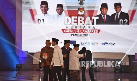 Ketua KPU Arief Budiman (kiri) bersama pasangan capres-cawapres nomor urut 01 Joko Widodo (kedua kiri) dan Ma'ruf Amin (kedua kanan) serta pasangan nomor urut 02 Prabowo Subianto (tengah) dan Sandiaga Uno (kanan) bersiap mengikuti debat pertama Pilpres 2019, di Hotel Bidakara, Jakarta, Kamis (17/1/2019). 