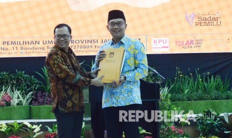 Ketua KPU Jawa Barat Rifqi Alimubarok (kiri) dan Gubernur Jawa Barat Ridwan Kamil saat penyerahan salinan Surat Keputusan Calon Terpilih Anggota DPRD Provinsi Jawa Barat 2019, di Kantor KPU Provinsi Jawa Barat, Kota Bandung, Rabu (14/8).