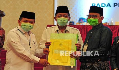 Ketua KPU Jambi Subhan (kanan) menyerahkan dokumen hasil rapat kepada Pasangan Calon Gubernur dan Wakil Gubernur Terpilih Al Haris (kiri) dan Abdullah Sani (tengah) saat Rapat Pleno Terbuka Penetapan Pasangan Calon Gubernur dan Wakil Gubernur Terpilih pada Pemilihan Gubernur dan Wakil Gubernur Jambi Tahun 2020, di Jambi, Sabtu (12/6/2021). KPU setempat menetapkan pasangan Al Haris - Abdullah Sani sebagai Gubernur dan Wakil Gubernur Jambi terpilih dengan perolehan suara 600.733 suara, mengungguli pasangan Cek Endra - Ratu Munawaroh dengan 587.918 suara, dan pasangan Fachrori Umar - Syafril Nursal dengan 381.634 suara.