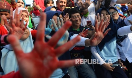 Ketua Lembaga Perlindungan Anak Indonesia (LPAI), Seto Mulyadi (tengah) bersama siswa menunjukan tangan kirinya seusai memberikan cap tangan di kain putih saat berlangsungya acara Stop Stigma di Gerbang Monas, Jakarta, Ahad (12/3).