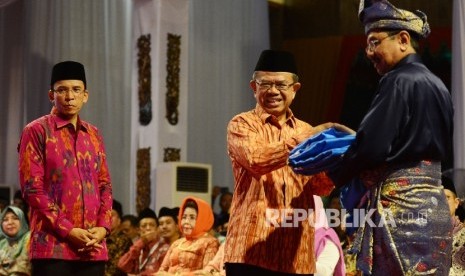  Ketua LPTQ Machasin (kedua kiri) memberikan bendera MTQ kepada PLT Gubernur Sumatera Utara Tengku Erry Nuradi (Kanan) disaksikan Gubernur Nusa Tenggara Barat TGH M. Zainul Majdi (kiri) saat menghadiri penutupan MTQ Nasional yang diadakan di Islamic Center