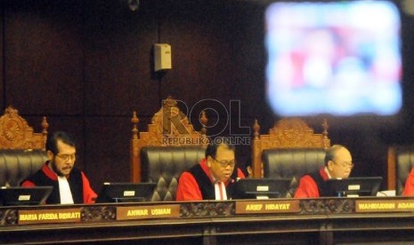 Ketua Mahkamah Konstitusi (MK) Arief Hidayat (tengah) didampingi Wakil Ketua MK Anwar Usman (kiri) dan Anggota Wahiduddin Adams membacakan putusan sidang tentang konstitusionalitas aturan setoran awal biaya haji Rp 25 juta di Jakarta, Selasa (20/10). 