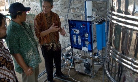 Ketua Masyarakat Nano Indonesia dan Pendiri Nanocenter Indonesia, Nurul Taufiqu Rochman (kanan), menjelaskan fungsi dan cara kerja alat penyulingan air, di Desa Penyaring, Kecamatan Moyo Utara, Kabupaten Sumbawa Besar, NTB.