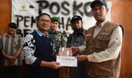 Ketua Pemulihan Bencana Sosial Tolikara, Edi Rante Tasa (kiri) menerima sumbangan sebesar Rp. 100.000 juta dari Manajer Layanan Badan Amil Zakat Nasional (Baznas) Agus Siswanto (kanan) di posko bencana sosial Tolikara, Papua, Jumat (24/7).