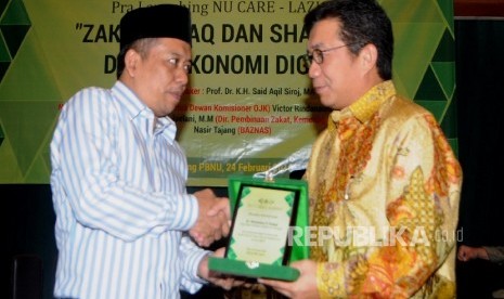 Ketua PP Lazis NU Syamsul Huda (kiri) menyerahkan cendera mata kepada Ketua Dewan Komisioner OJK Muliaman D Hadad pada acara Seminar Pra-Launching NU Care Laziznu, dengan tema “Zakiat, Infak, dan Sedekah di Era Ekonomi Digital” di Jakarta, Rabu (24/2).