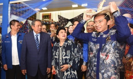 Ketua Umum Partai Demokrat Susilo Bambang Yudhoyono (kedua kiri) dan Ibu Ani Yudhoyono (kedua kanan), memperhatikan Ketua Fraksi Edhie Baskoro Yudhoyono (kanan) mengenakan topi tradisional saat meninjau stan daerah sebelum menghadiri puncak peringatan HUT 