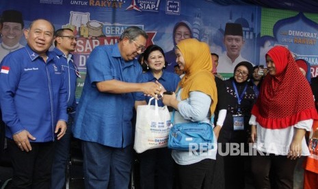 Ketua Umum Partai Demokrat Susilo Bambang Yudhoyono (kedua kiri) didampingi Ibu Ani Yudhoyono dan Politisi Partai Demokrat Nachrowi Ramli (kiri) memberikan paket sembako yang telah dibeli oleh warga saat acara Gerakan Pasar Murah Demokrat di Wisma Proklamasi, Jakarta, Kamis (7/6).