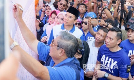 Ketua Umum Partai Demokrat Susilo Bambang Yudhoyono (SBY), Agus Harimurti Yudhoyono (AHY), dan Tuan Guru Bajang (TGB) Muhammad Zainul Majdi menandatangani banner stop hoax dan fitnah di Car Free Day di Mataram, NTB, Ahad (7/5).