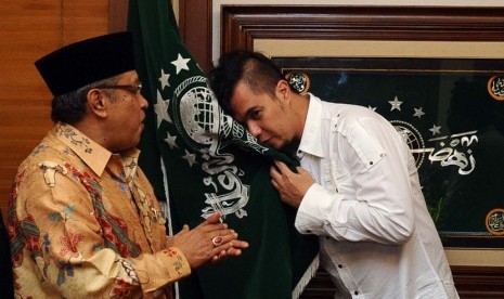  Ketua Umum PBNU, Said Aqil Siroj (kiri), menyaksikan Ketua Seni dan Kebudayaan NU, Ahmad Dhani (kanan), mencium bendera NU usai memberikan pin ketua Seni dan Kebudayaan dalam tasyakuran Harlah PBNU ke 91 di Jakarta, Jumat (16/5). 