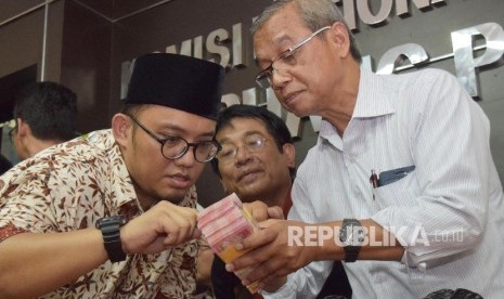   Ketua Umum Pemuda Muhammadiyah, Dahnil Anzar Simanjuntak (kiri), bersama Ketua PP Muhammadiyah Busyro Muqqodas (kanan) memeriksa uang dari Densus 88 untuk keluarga almarhum Siyono di kantor Komnas HAM, Jakarta, Senin (11/4). (Republika/Rakhmawaty La'lang