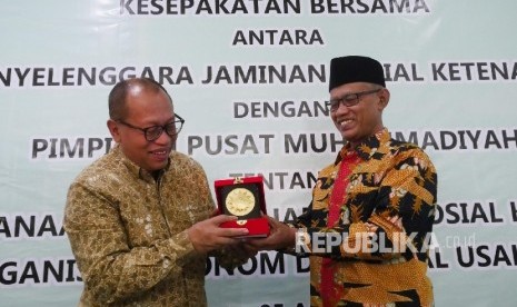  Ketua Umum PP Muhammadiyah Haedar Nashir (kiri) menyerahkan cinderamata kepada Direktur Utama BPJS Ketenagakerjaan Agus Susanto usai acara penendatangan kerjasama antara BPJS Ketenagakerjaan dan Muhammdiyah di Jakarta, Rabu (5/4). 