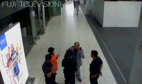 Kim Jong-nam (berjas abu-abu) berbicara kepada petugas keamanan setelah dirinya diserang perempuan di wajah.